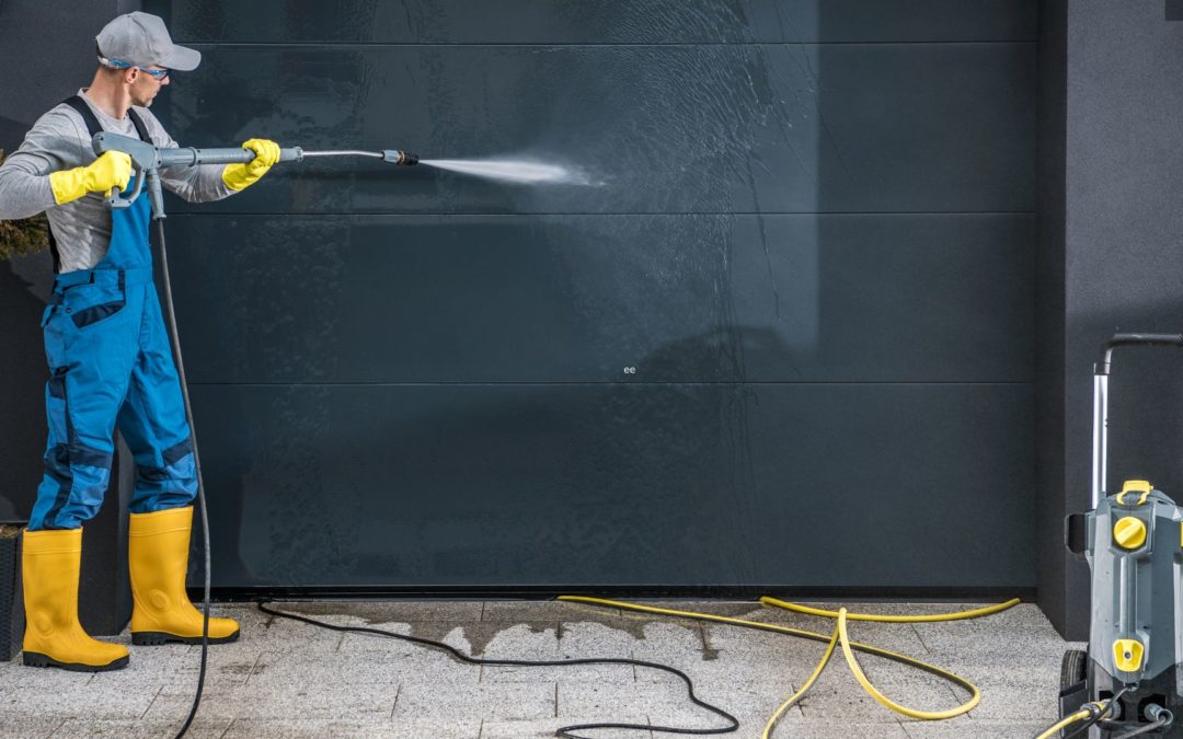 A man cleans his garage door, using one of the three fall maintenance tips for garage doors