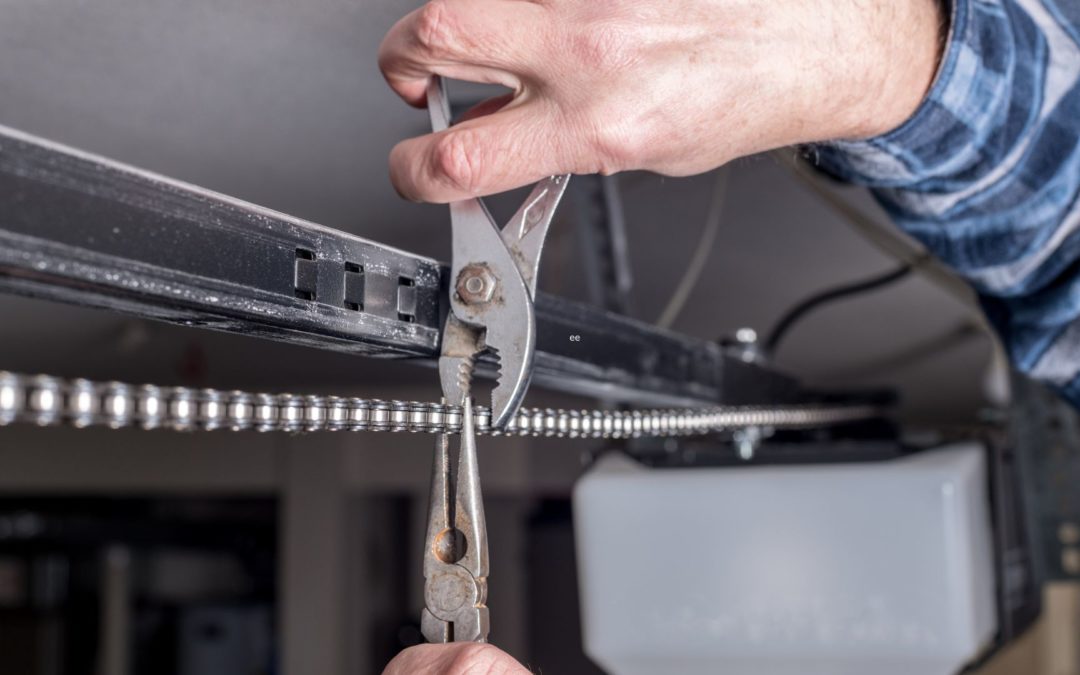 A man tightens hardware on his garage door, using one of the three fall maintenance tips for garage doors